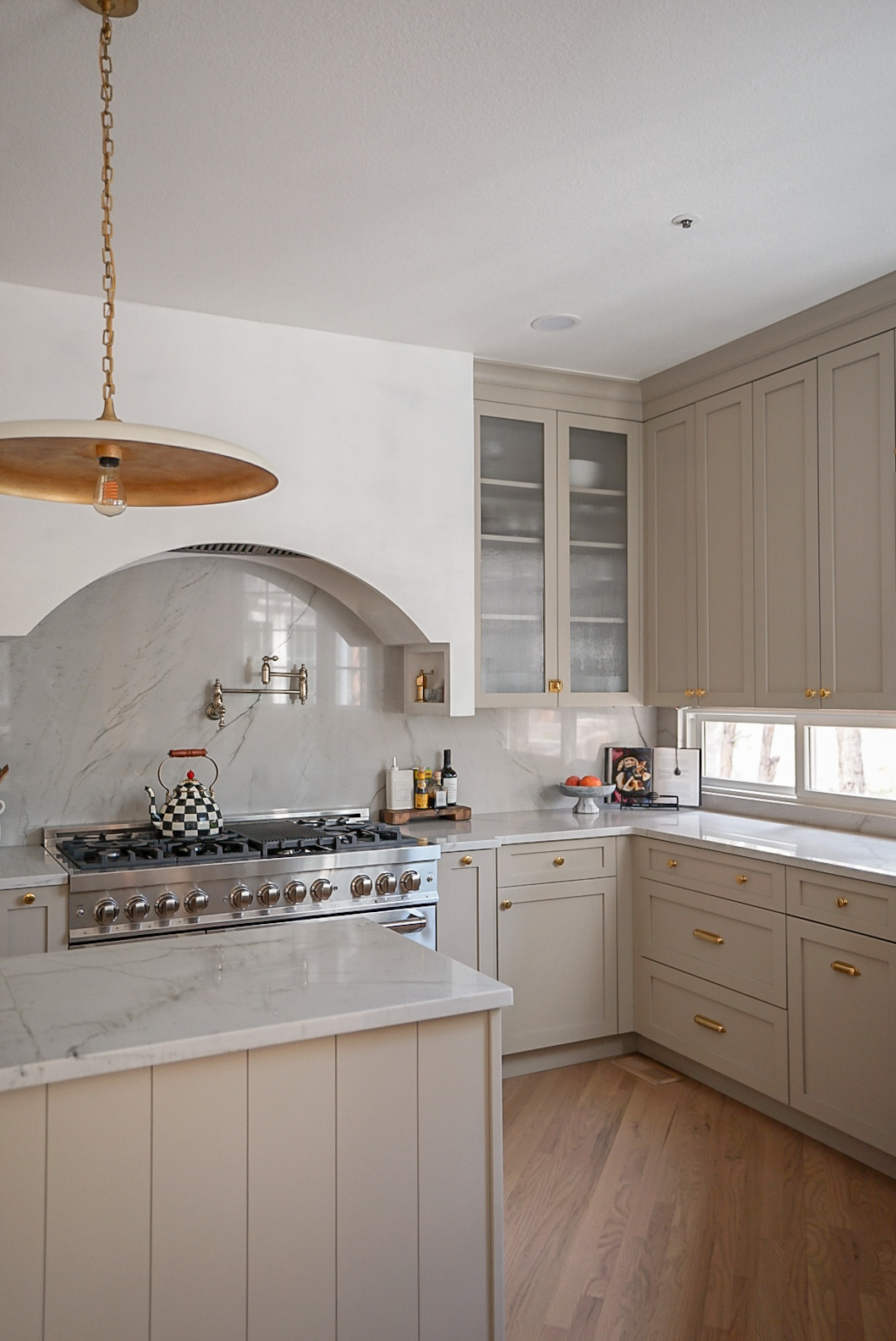 Custom cabinet detail with unlacquered brass knobs and pulls in warm taupe kitchen