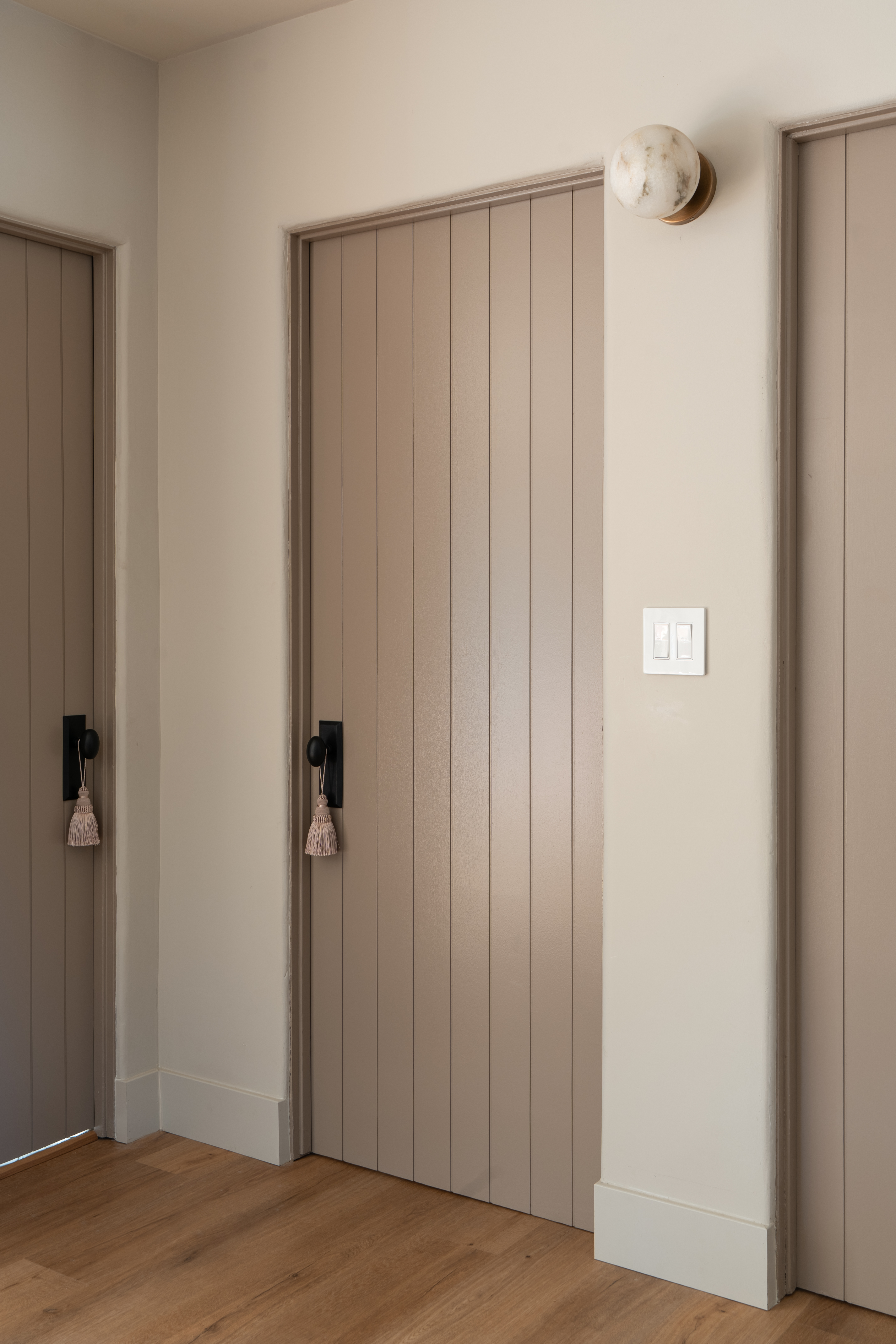 Detail of a tasseled door pull against painted wood paneling in Palm Springs interior